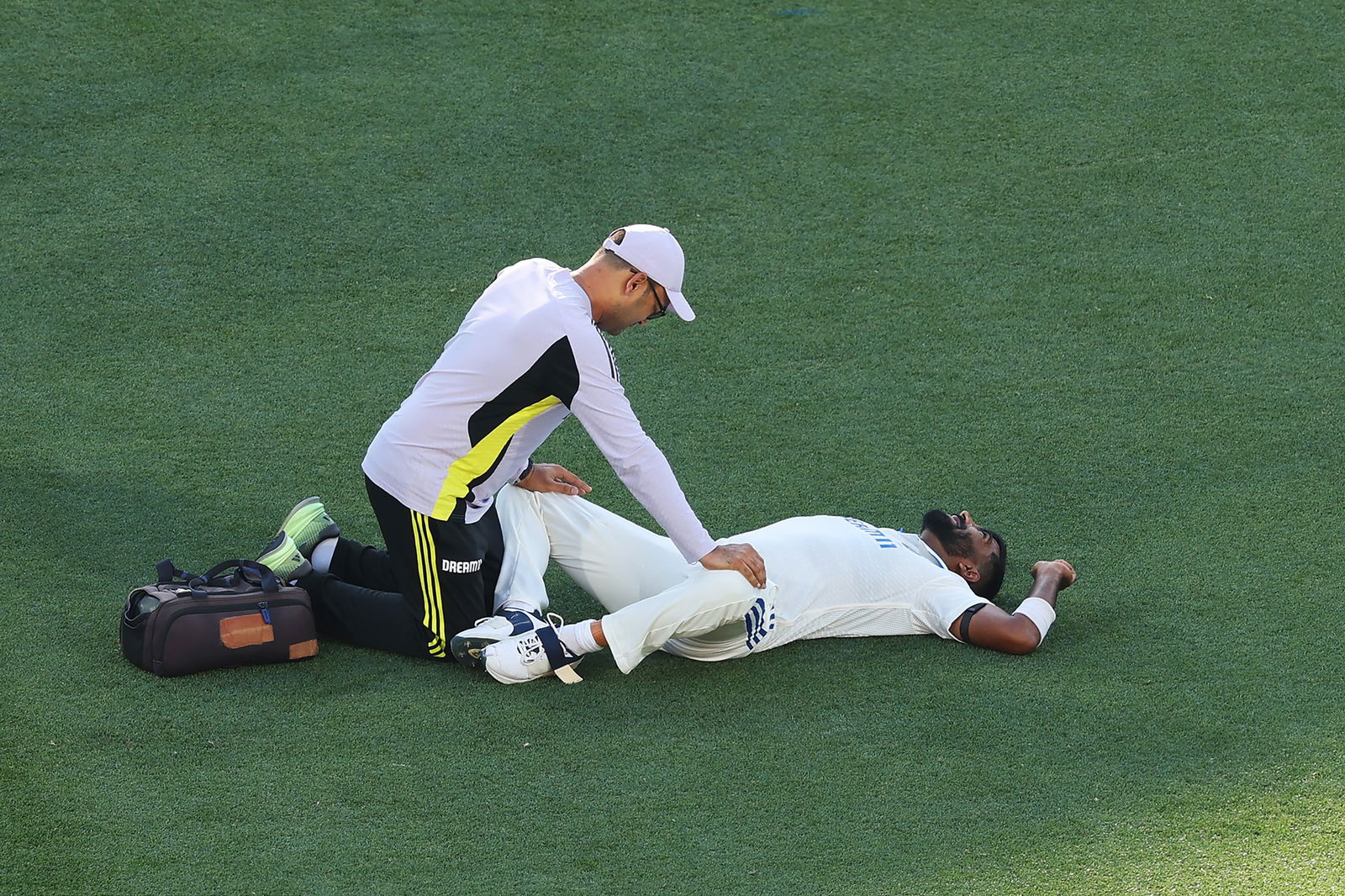 Jasprit Bumrah gets worked on by a trainer after cramping on day two.